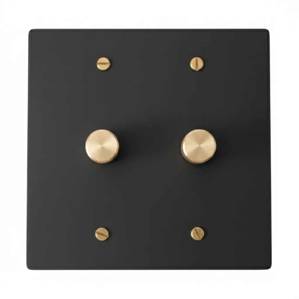Black dimmer switch with gold circular knobs on a white background
