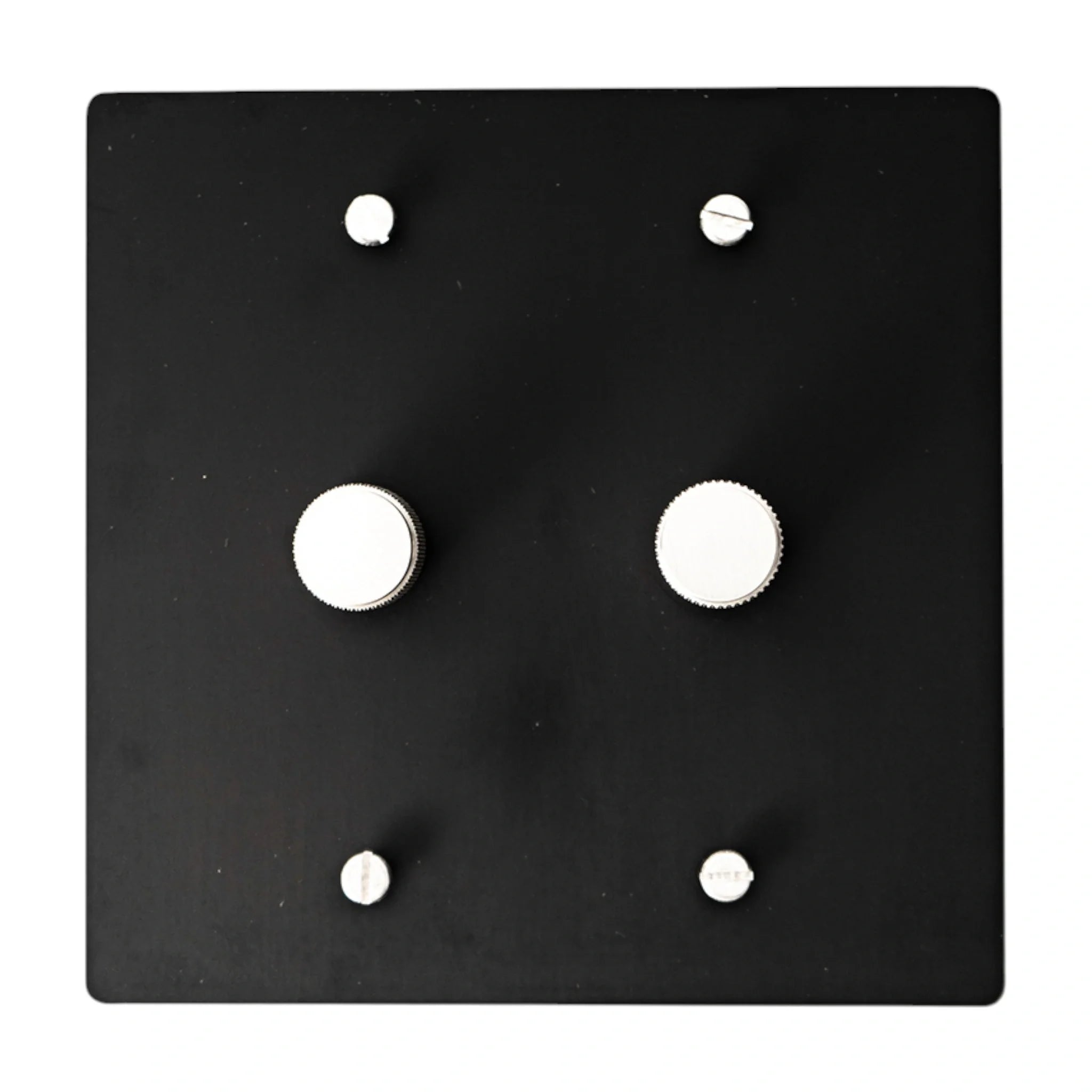 Black square wall plate with silver knobs and screws on a white background