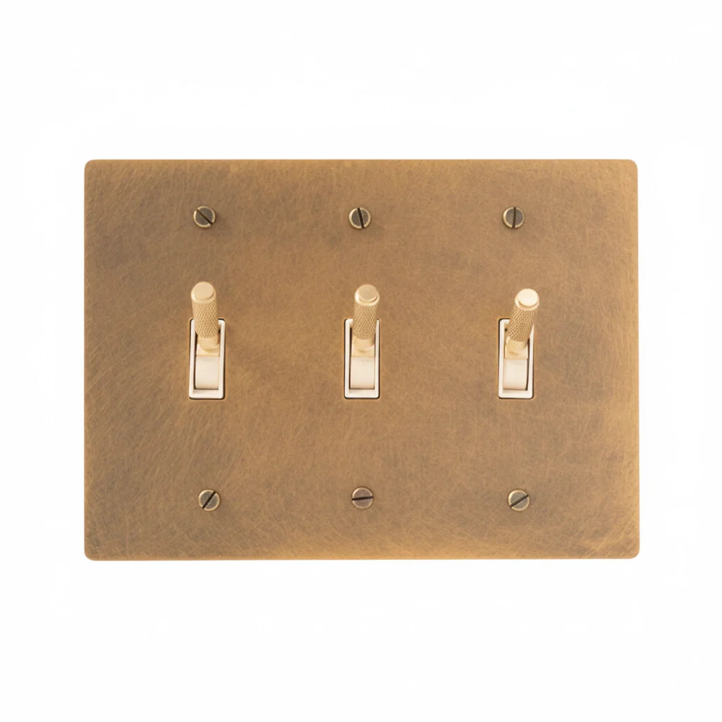 Close-up of knurled toggle detail on antique brass 3-gang switch plate