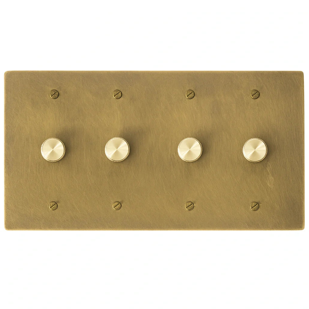 Four gang antique brushed brass dimmer switch panel with smooth rotary knobs and matching brass screws.