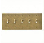 Close-up of knurled toggles on unlacquered antique brass 5-gang switch plate