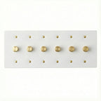 White 6 gang brass dimmer wall plate with gold screws on a white background
