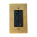 black electrical outlet on a antique brushed brass wall plate with screws