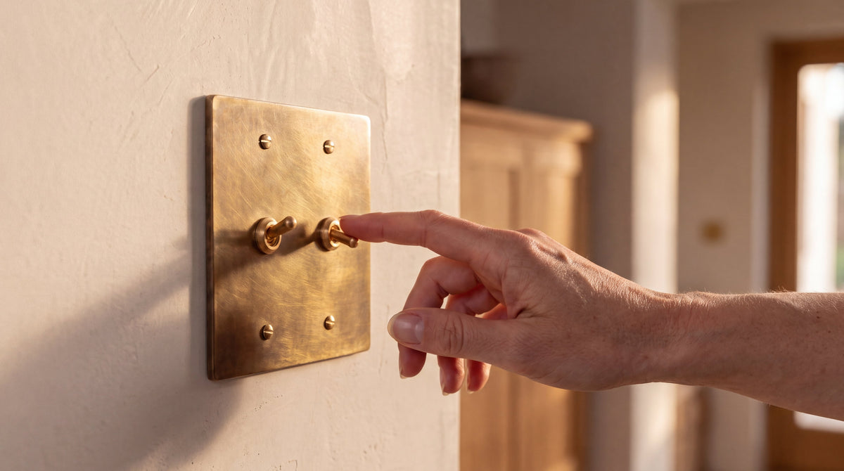 2-Gang Solid Brass Retro Toggle Light Switch in Unlacquered Antique Brass being used by hand